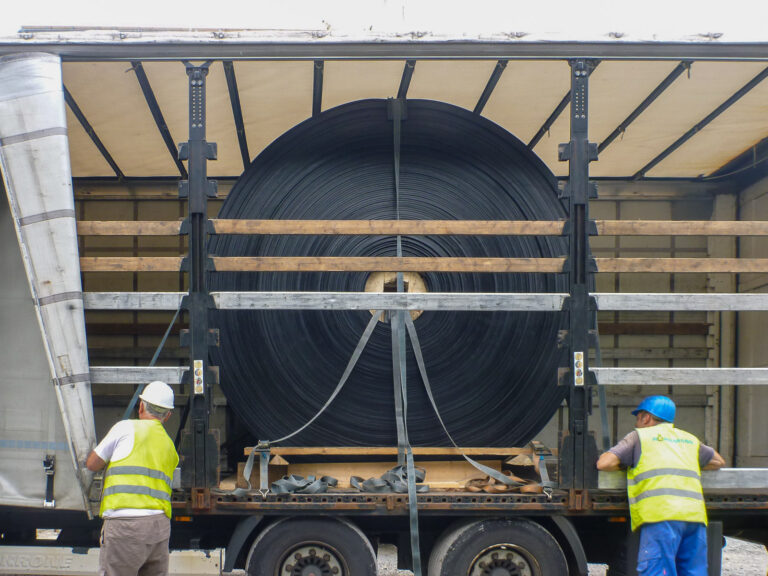 Arbeiter sichern große Gummirolle auf LKW