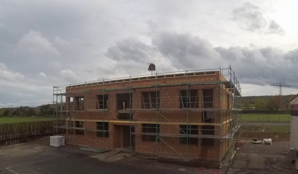 Unvollendetes Backsteingebäude mit Gerüst bei bewölktem Himmel